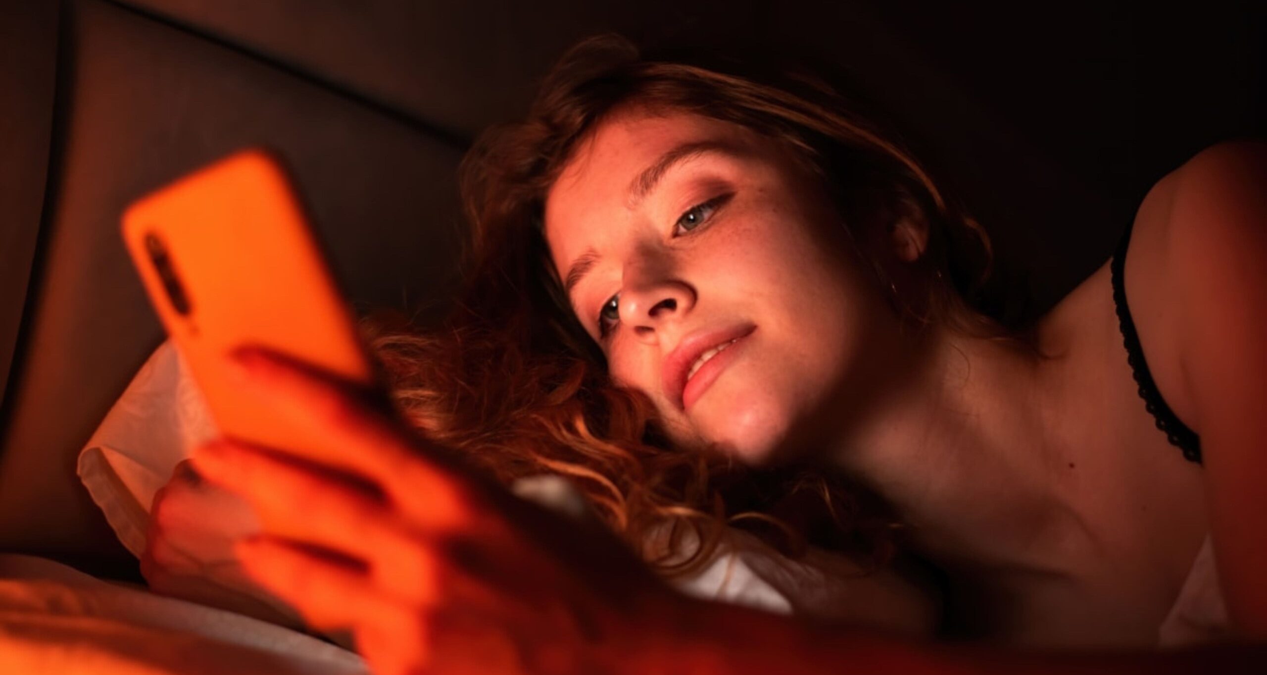 woman using her phone to manage multiple eSIM profiles for seamless IoT connectivity, showcasing the ease of global communication and device management.