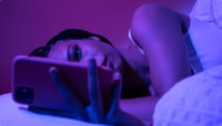 A woman smiling while using her phone, enjoying seamless connectivity through Valid's Multi-IMSI Alliance solution.