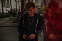 A young man standing on the street, enjoying the seamless activation of his eSIM through a mobile app. The image highlights the convenience and efficiency of in-APP eSIM activation, part of Valid's new series showcasing eSIM onboarding journeys, which includes use cases like Generic QR code and Individual QR code.